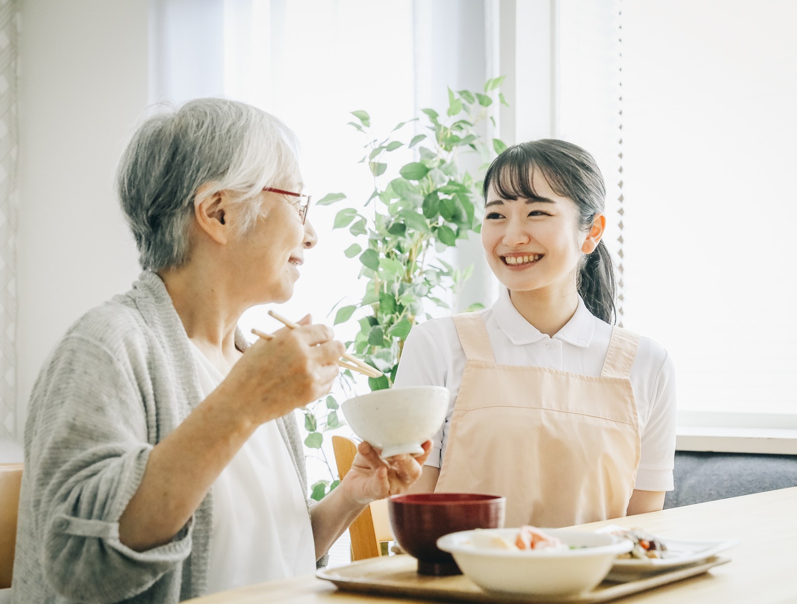 介護職員が利用者さんの食事に付き添う様子